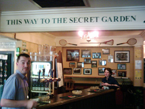 Bemused barmaid looking at Rich pointing to secret garden, The Club House